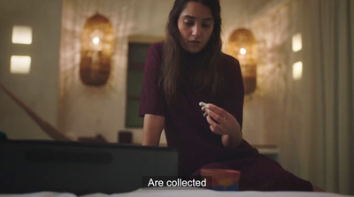 a woman sitting on a bed looking at her cell phone