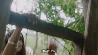 a woman holding onto a tree branch in a forest