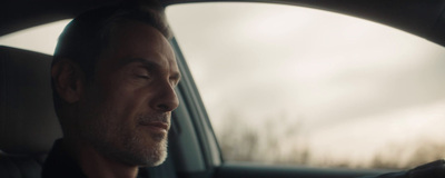 a man sitting in a car with his eyes closed