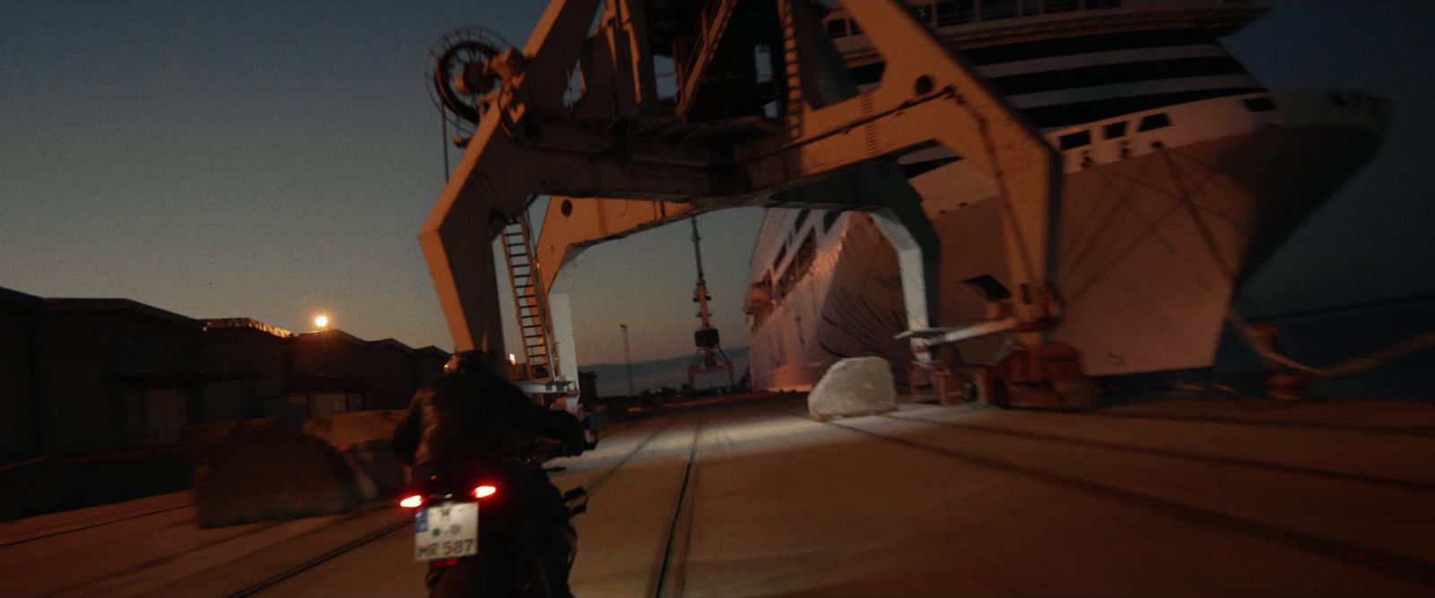 a man riding a motorcycle next to a large ship