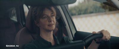 a woman sitting in a car with a steering wheel