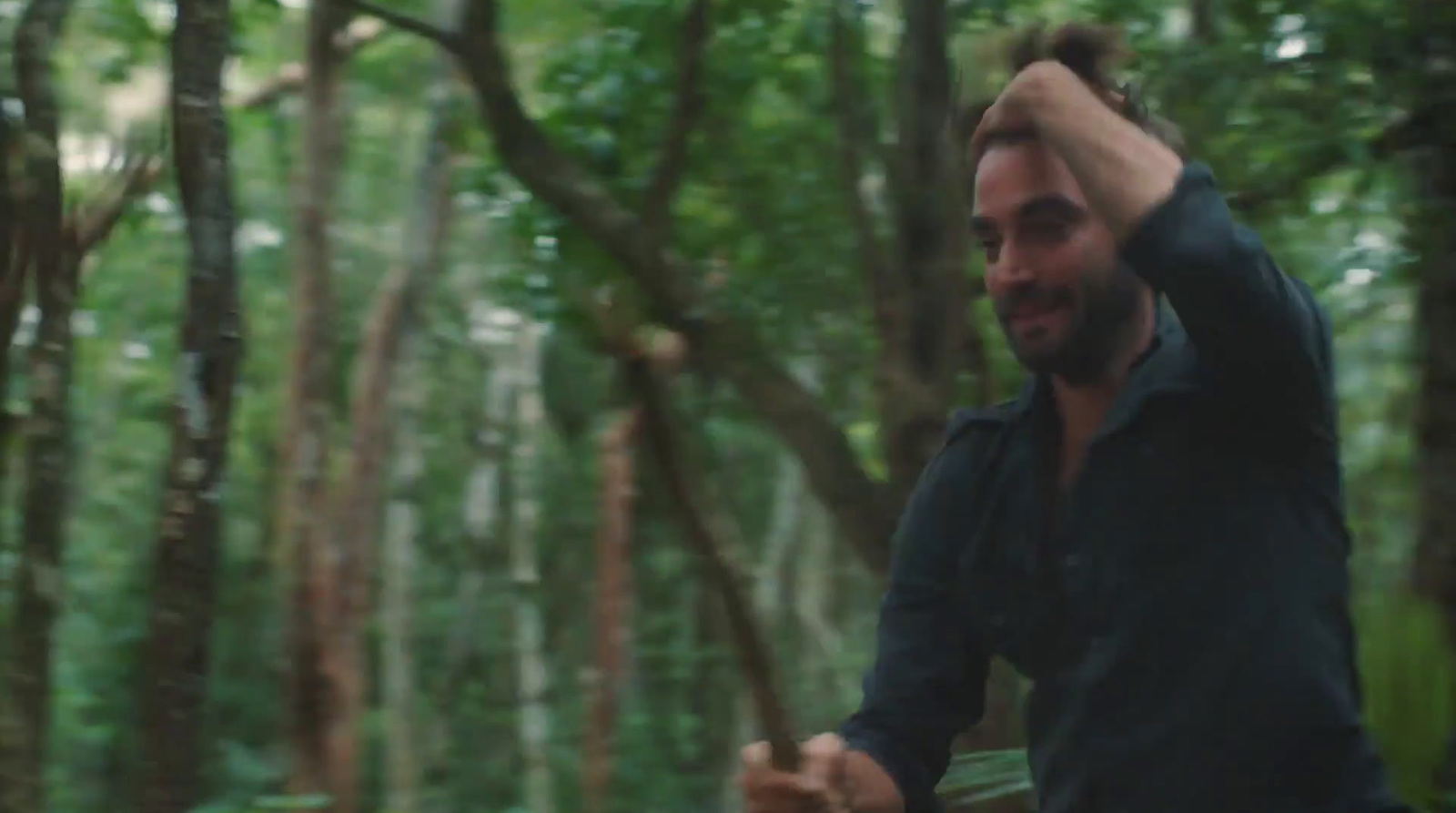 a man standing in the middle of a forest holding a frisbee