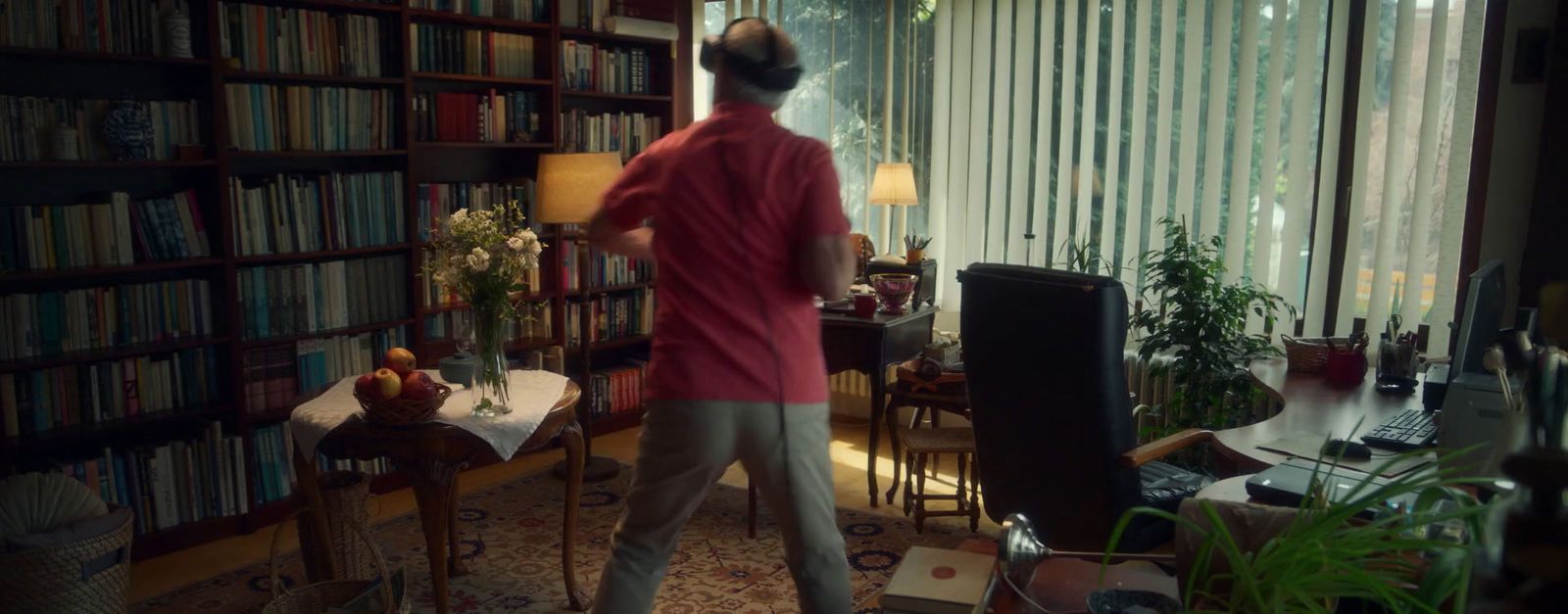 a woman standing in a living room next to a book shelf