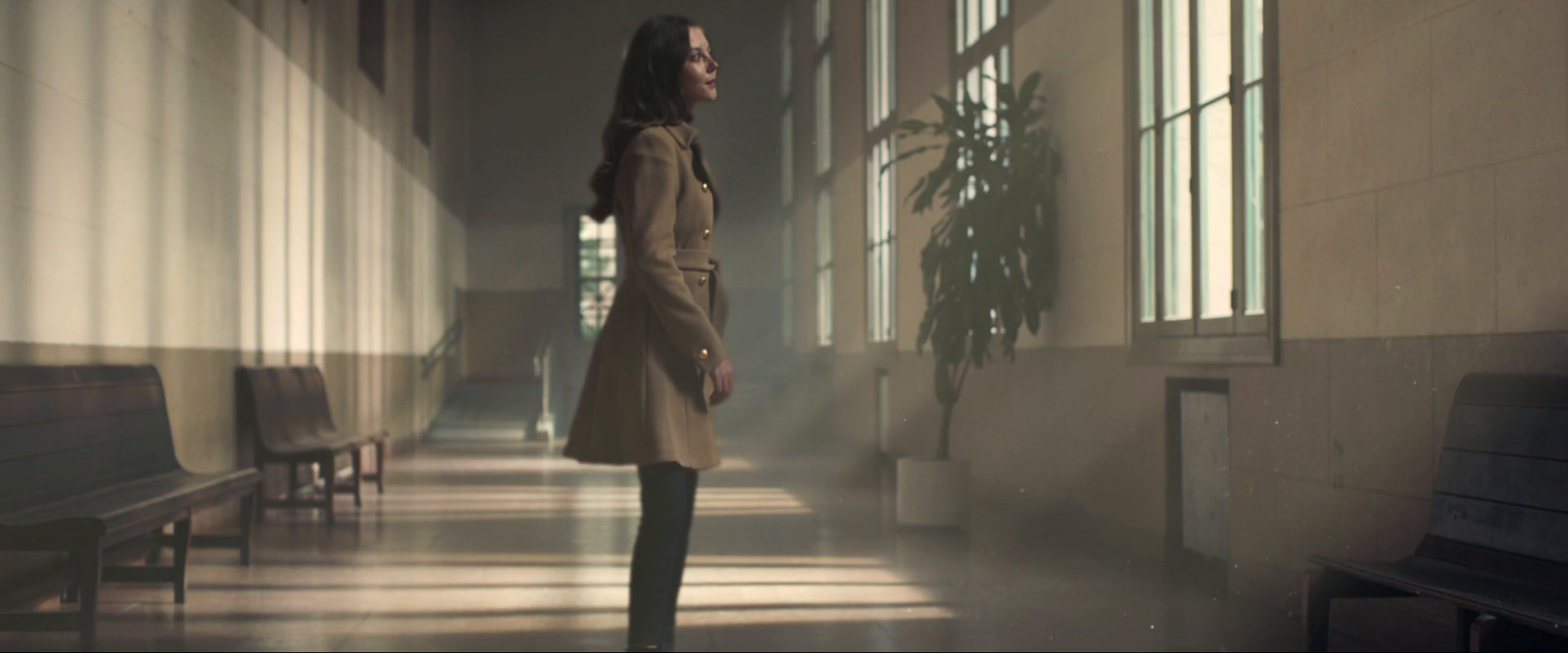 a woman standing in a hallway next to a piano