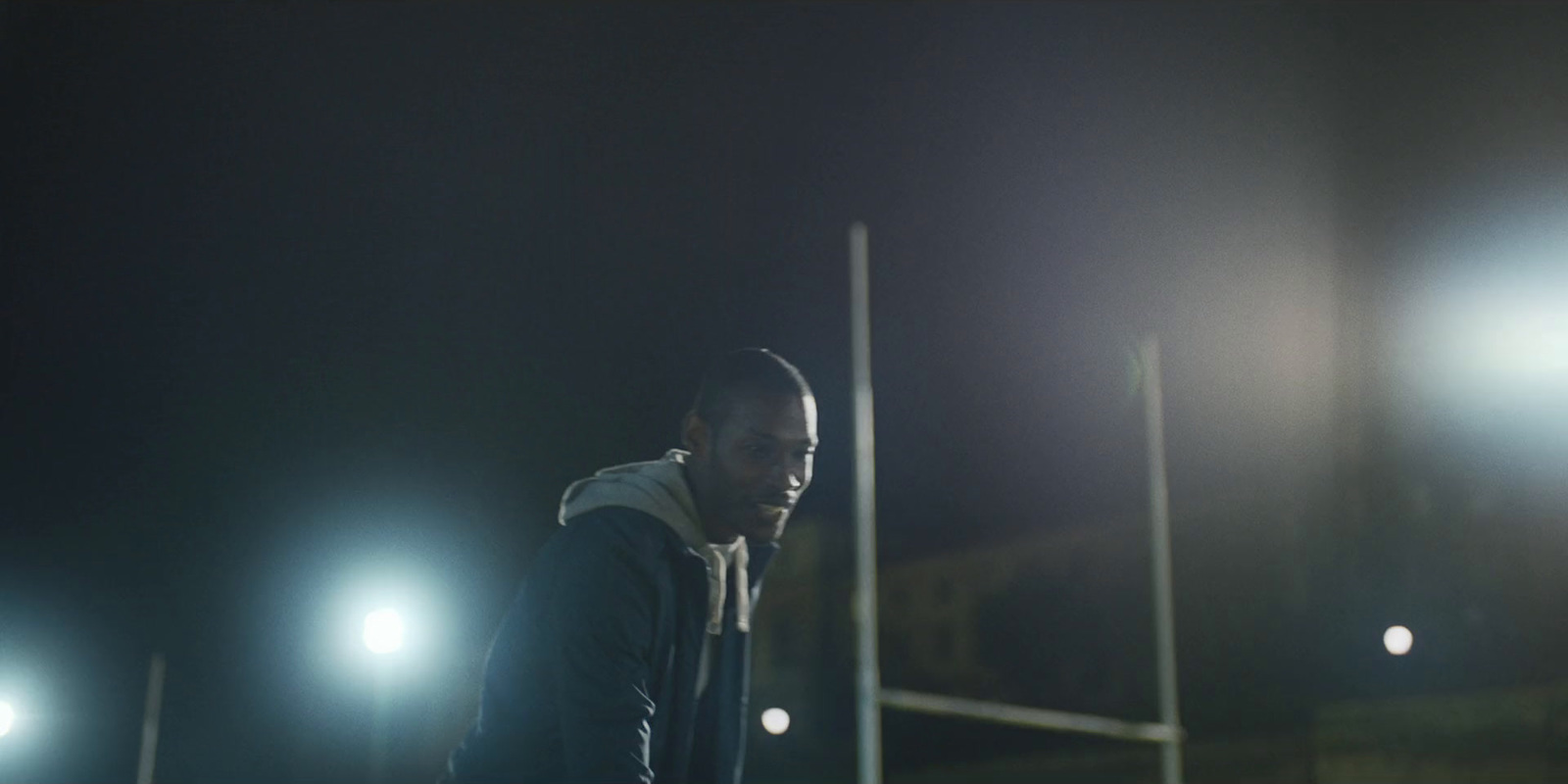 a man in a hoodie standing on a field at night