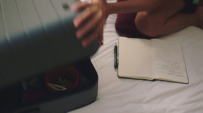 a person sitting on a bed with a book and a pen