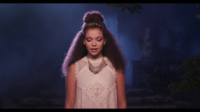 a woman with long hair standing in front of a dark background