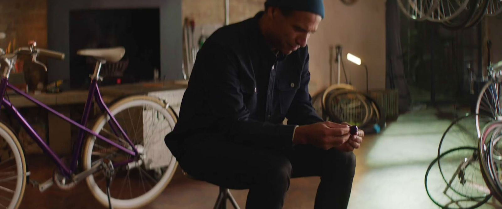 a man sitting on a stool looking at his cell phone