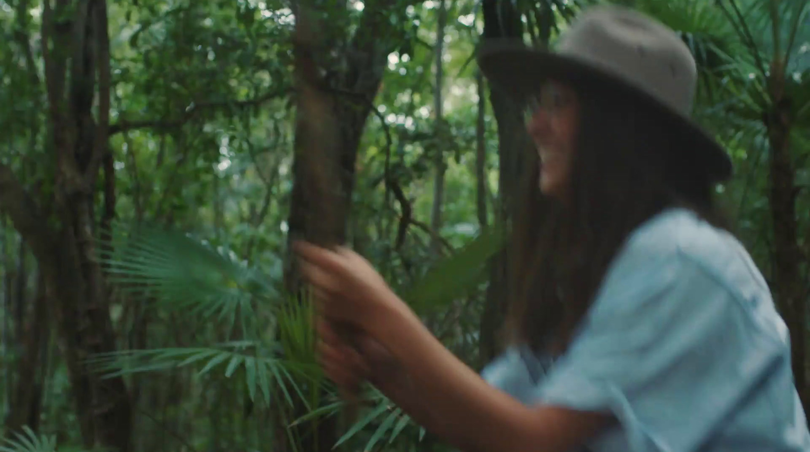 a man in a hat standing in a forest