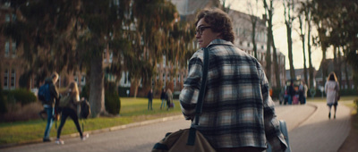 a man in a plaid jacket walking down a sidewalk