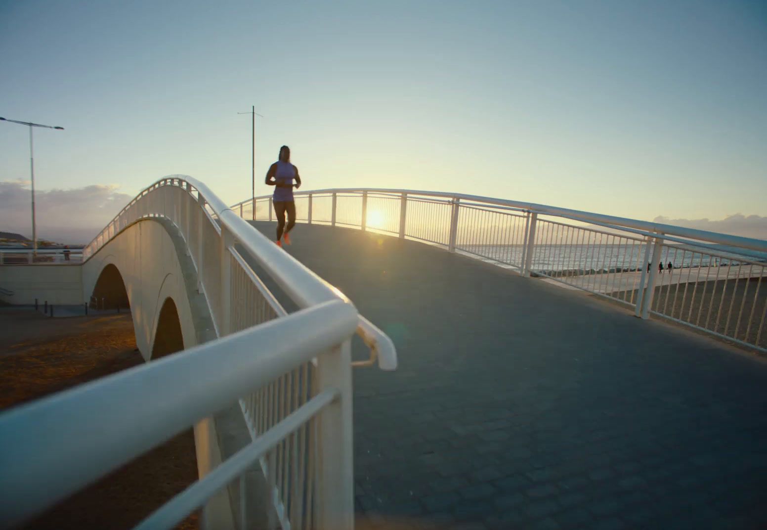 a man running across a bridge at sunset