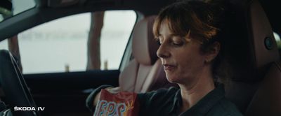 a woman sitting in a car holding a bag of chips