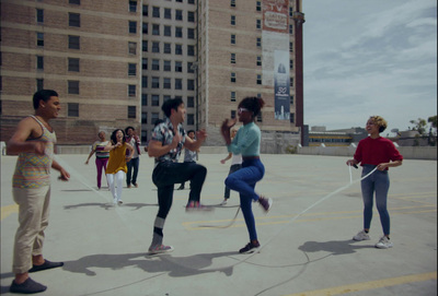 a group of people playing a game of skipping rope in a parking lot