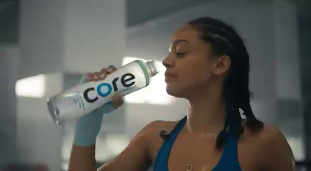 a woman drinking a bottle of core water