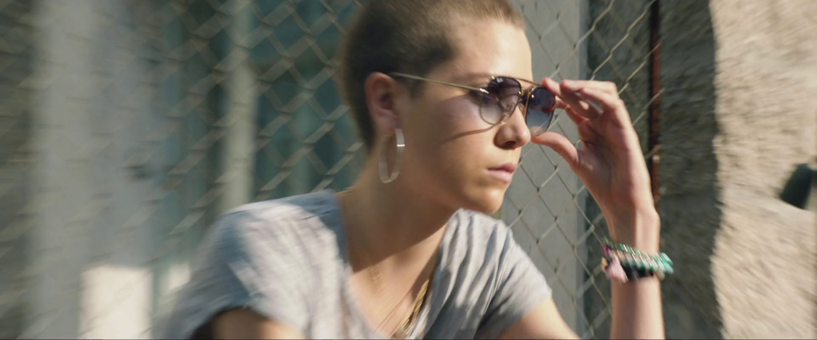 a woman wearing sunglasses leaning against a fence