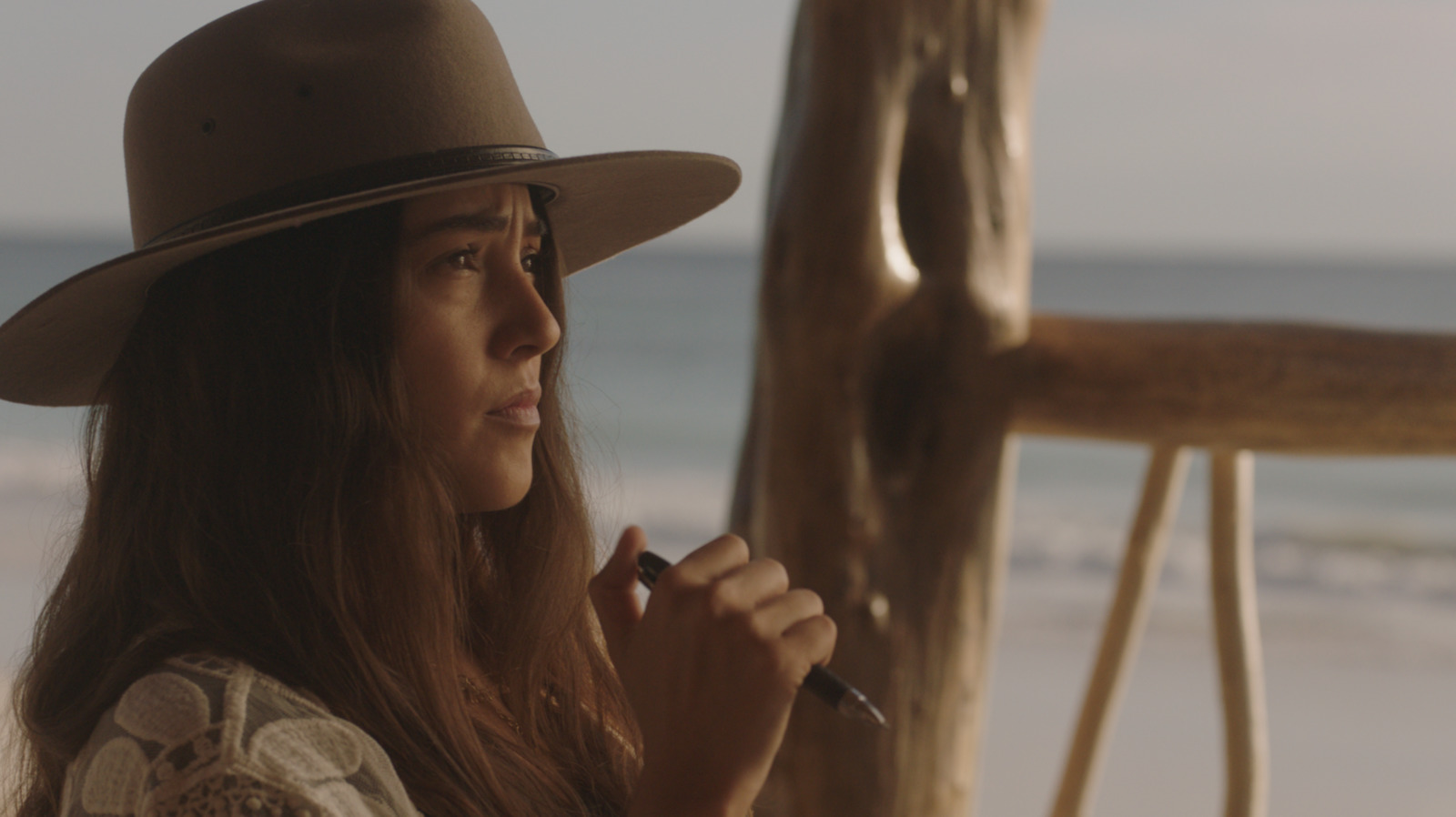 a woman wearing a hat and holding a pen