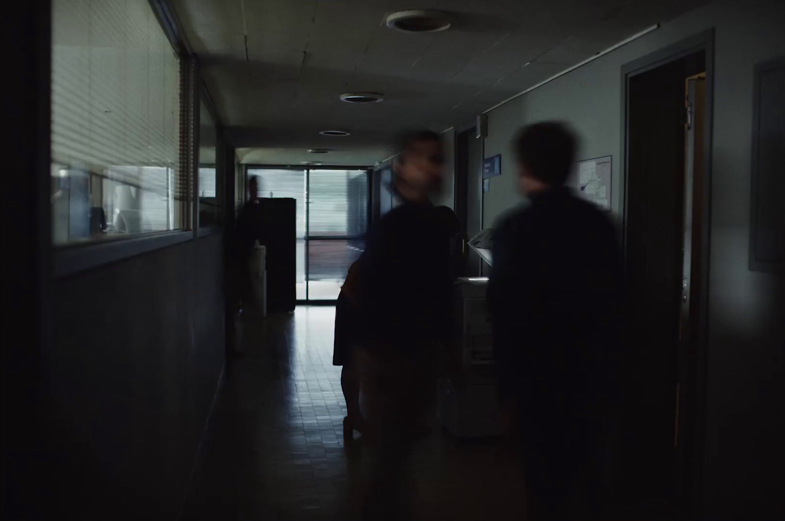 two people walking down a hallway in a dark room