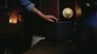 a person holding onto a black box on a table