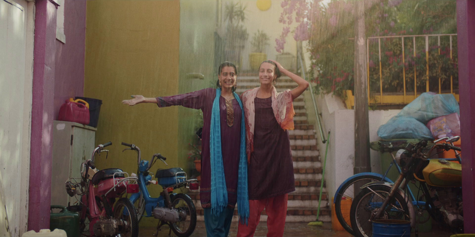 two women standing in front of a pink wall