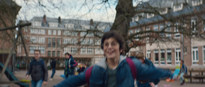 a boy in a blue jacket is running in a park