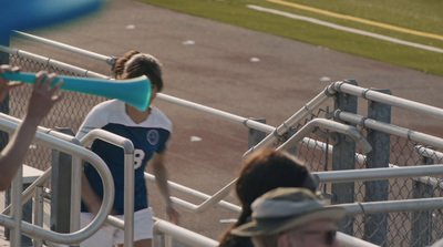 a woman holding a baseball bat on top of a baseball field