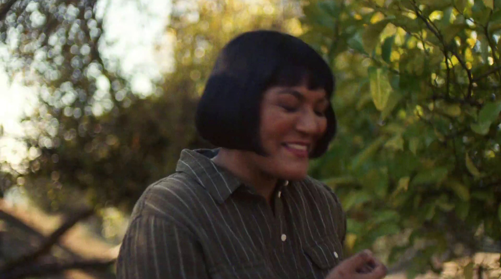 a woman standing in front of a tree smiling