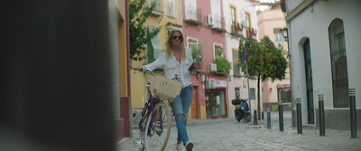 a woman riding a bike down a cobblestone street