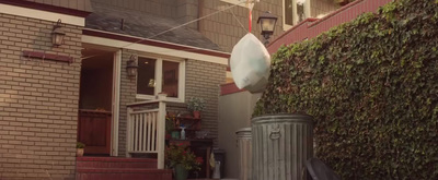 a house with a fence and a trash can in front of it