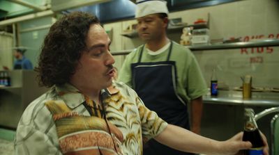 a man holding a bottle of wine in a kitchen