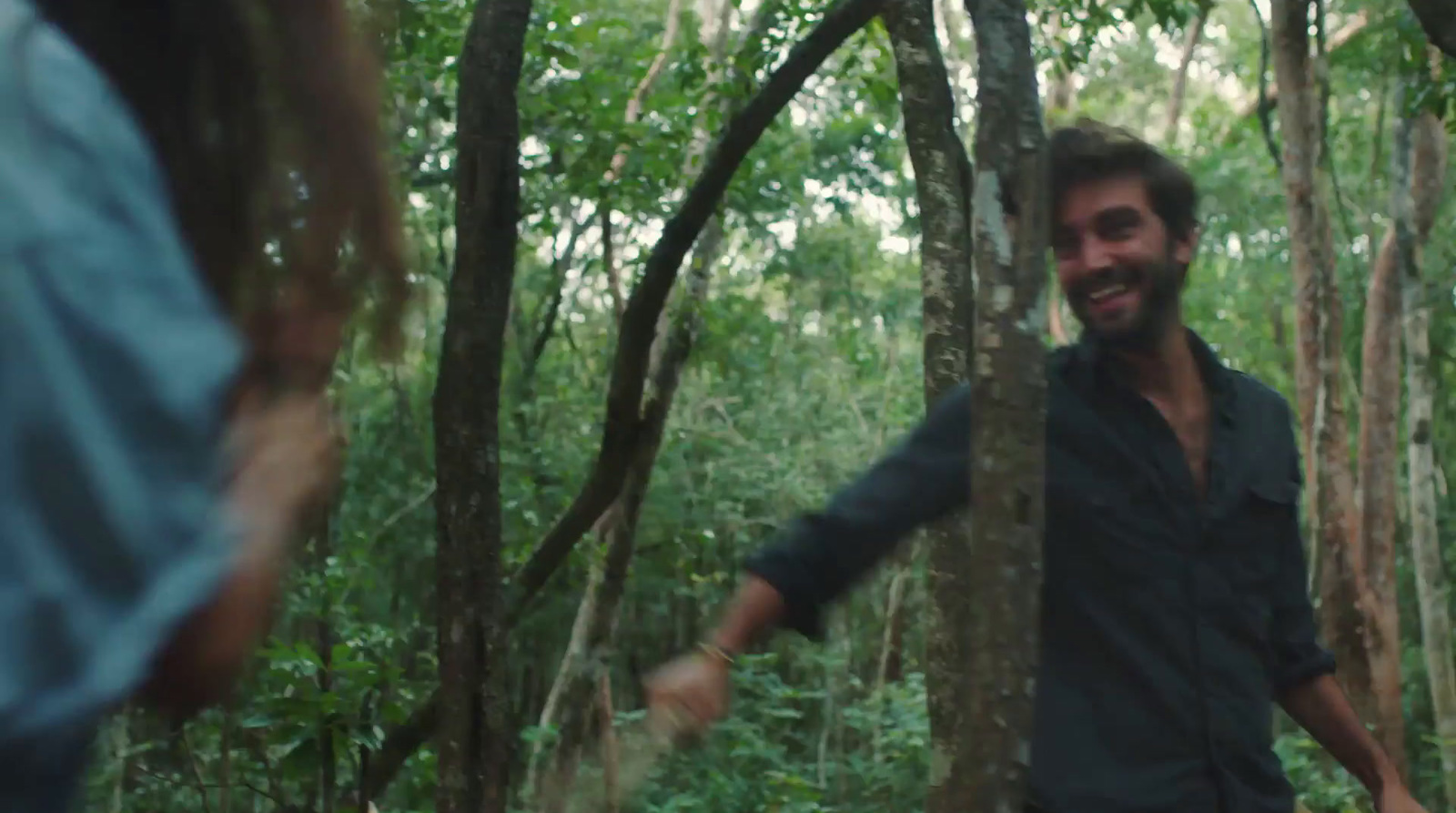 a man and a woman walking through a forest