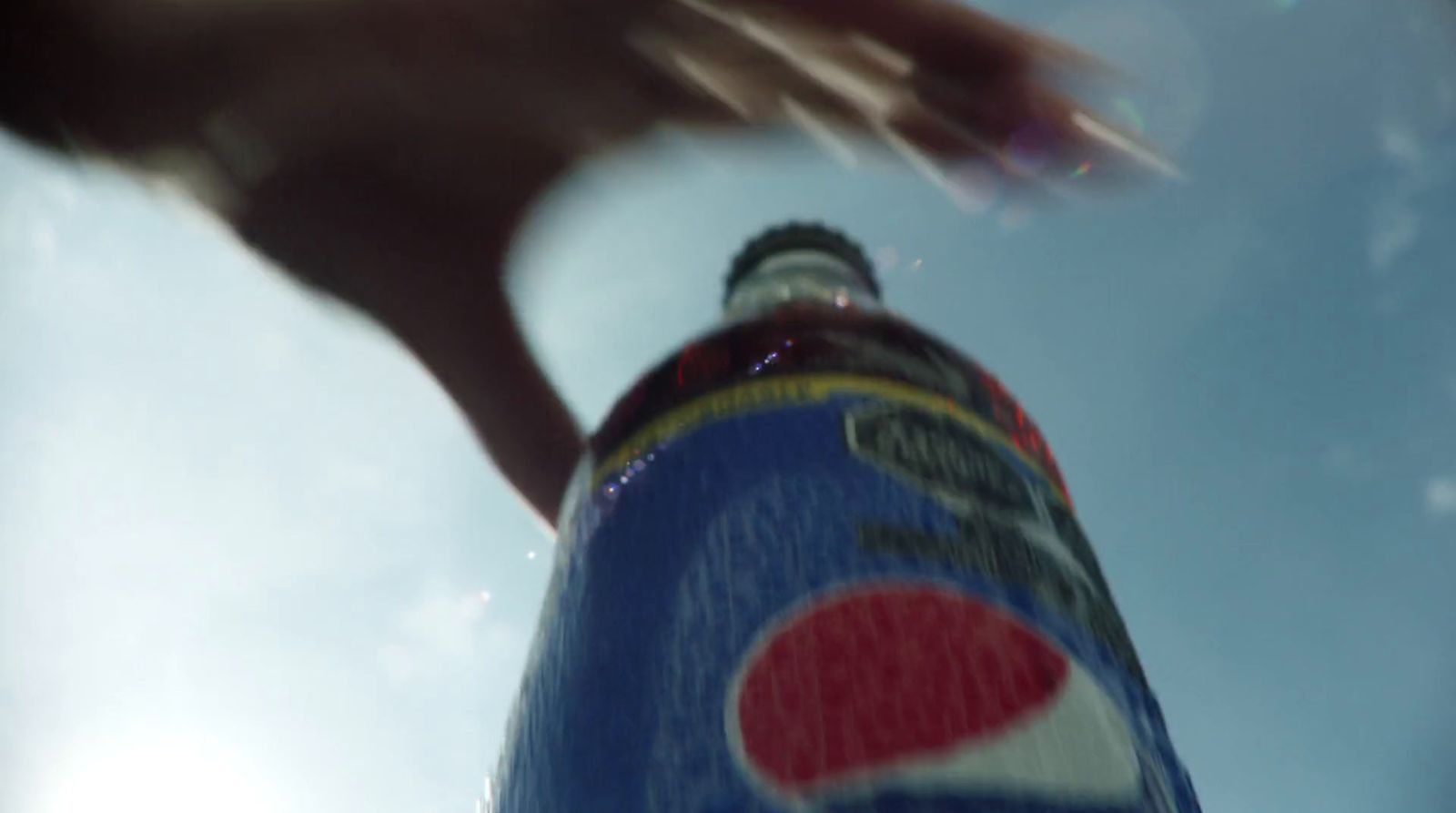 a close up of a pepsi bottle with a sky background