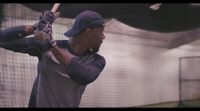 a man holding a baseball bat in a batting cage