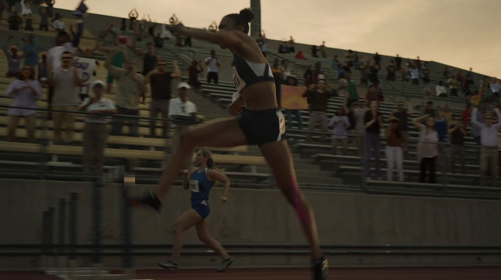 a woman is running on a track in front of a crowd