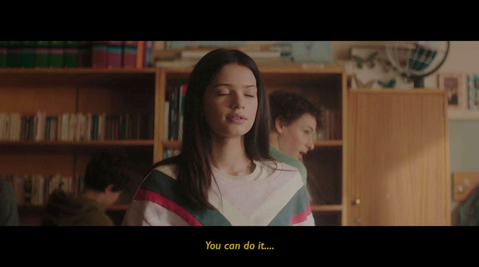 a girl is standing in front of a bookcase in a library