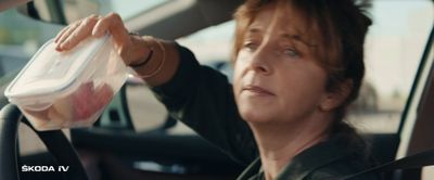 a woman sitting in a car holding a plastic container