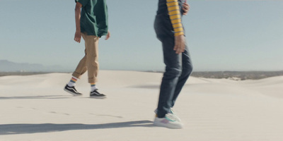 two people standing on top of a sand dune