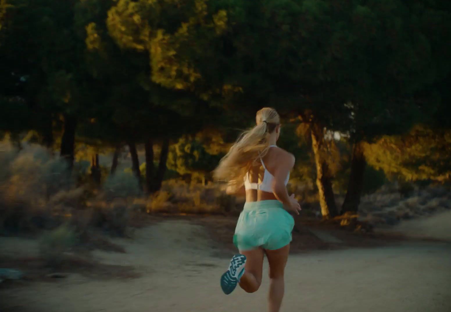 a woman running down a dirt road with trees in the background