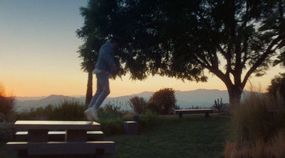 a man jumping in the air near a bench