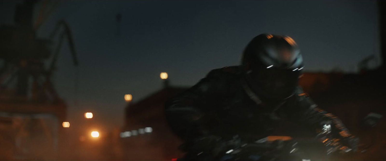 a man riding a motorcycle down a street at night