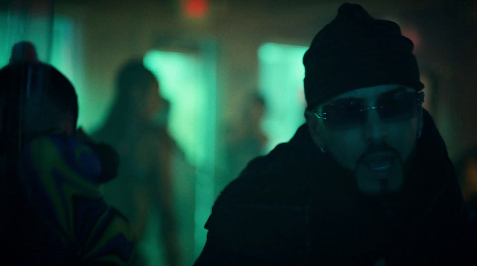 a man wearing sunglasses and a beanie in a dark room