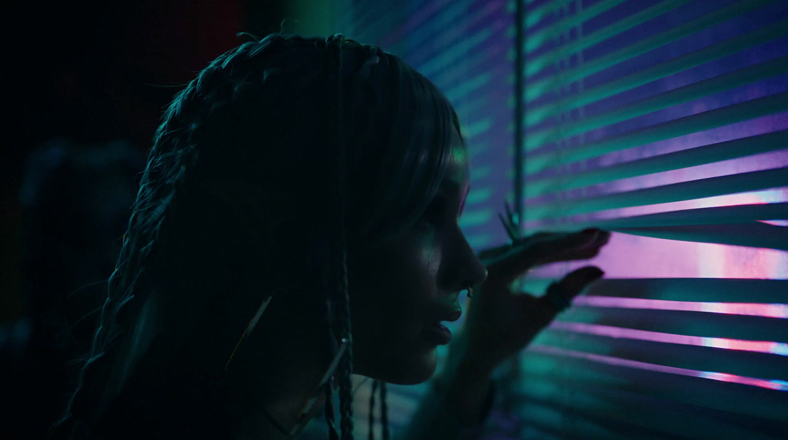 a woman standing next to a window covered in blinds