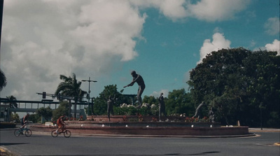 a man riding a bike down a street next to a statue