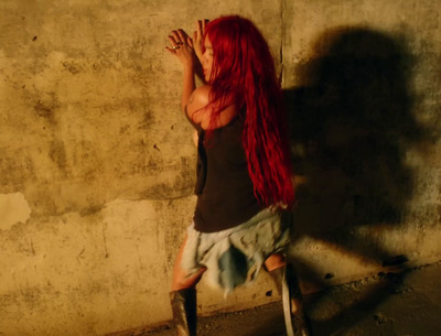 a woman with long red hair leaning against a wall