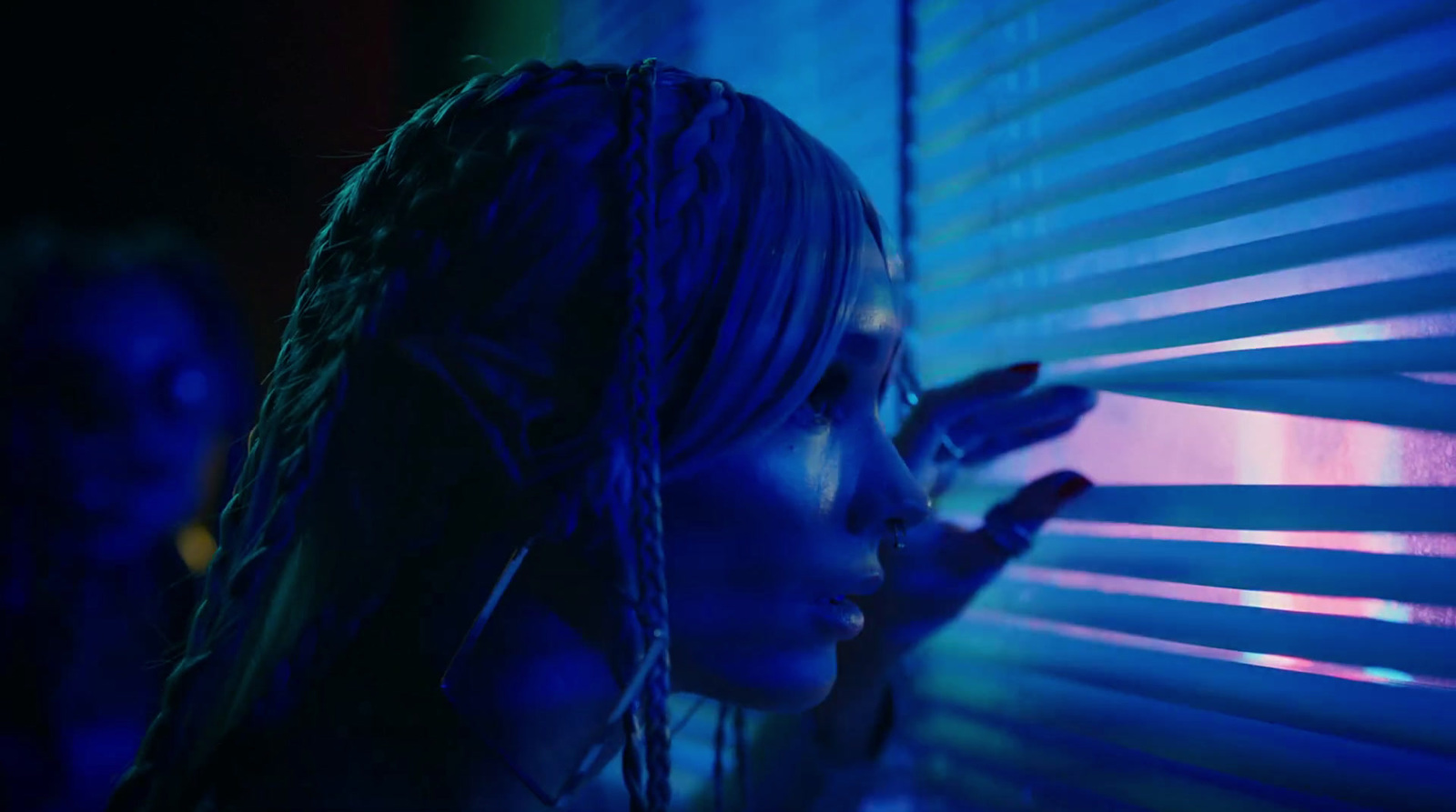 a woman standing next to a window covered in blue light