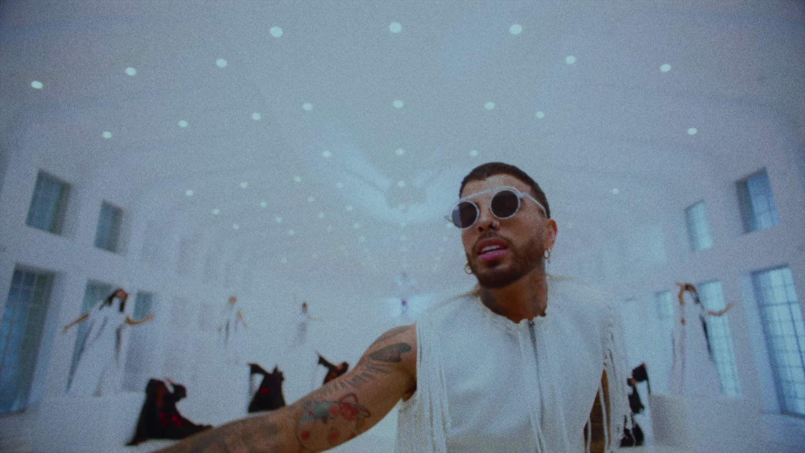 a man wearing sunglasses and a white vest