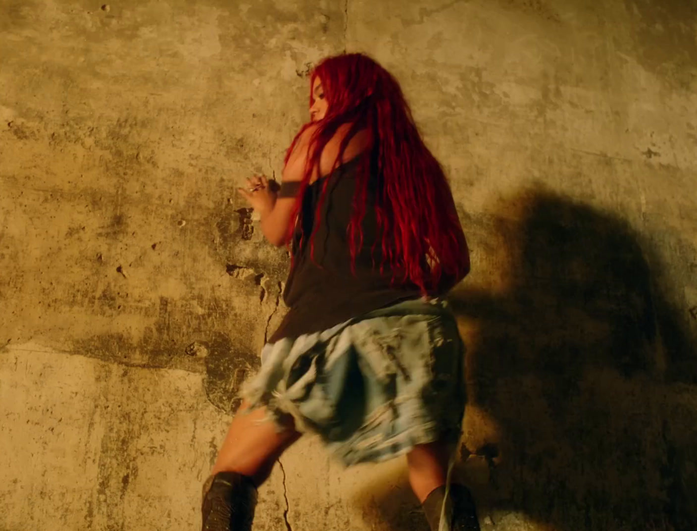 a woman with long red hair and boots walking up a ramp