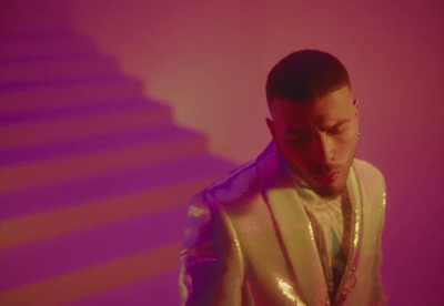 a man in a white suit standing in front of a stair case