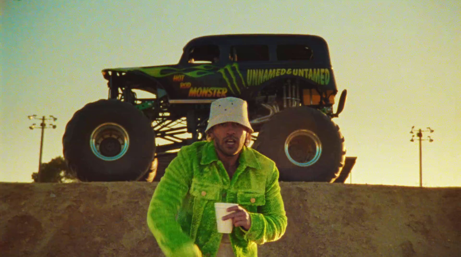 a man in a green jacket holding a cup