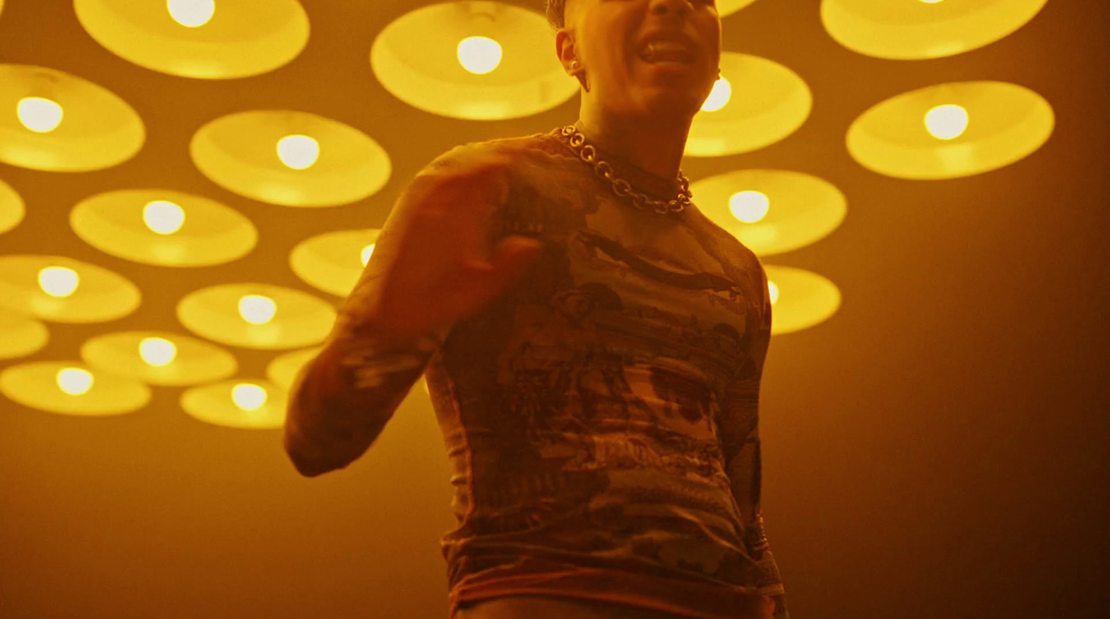 a man with tattoos on his arm standing in front of a yellow light