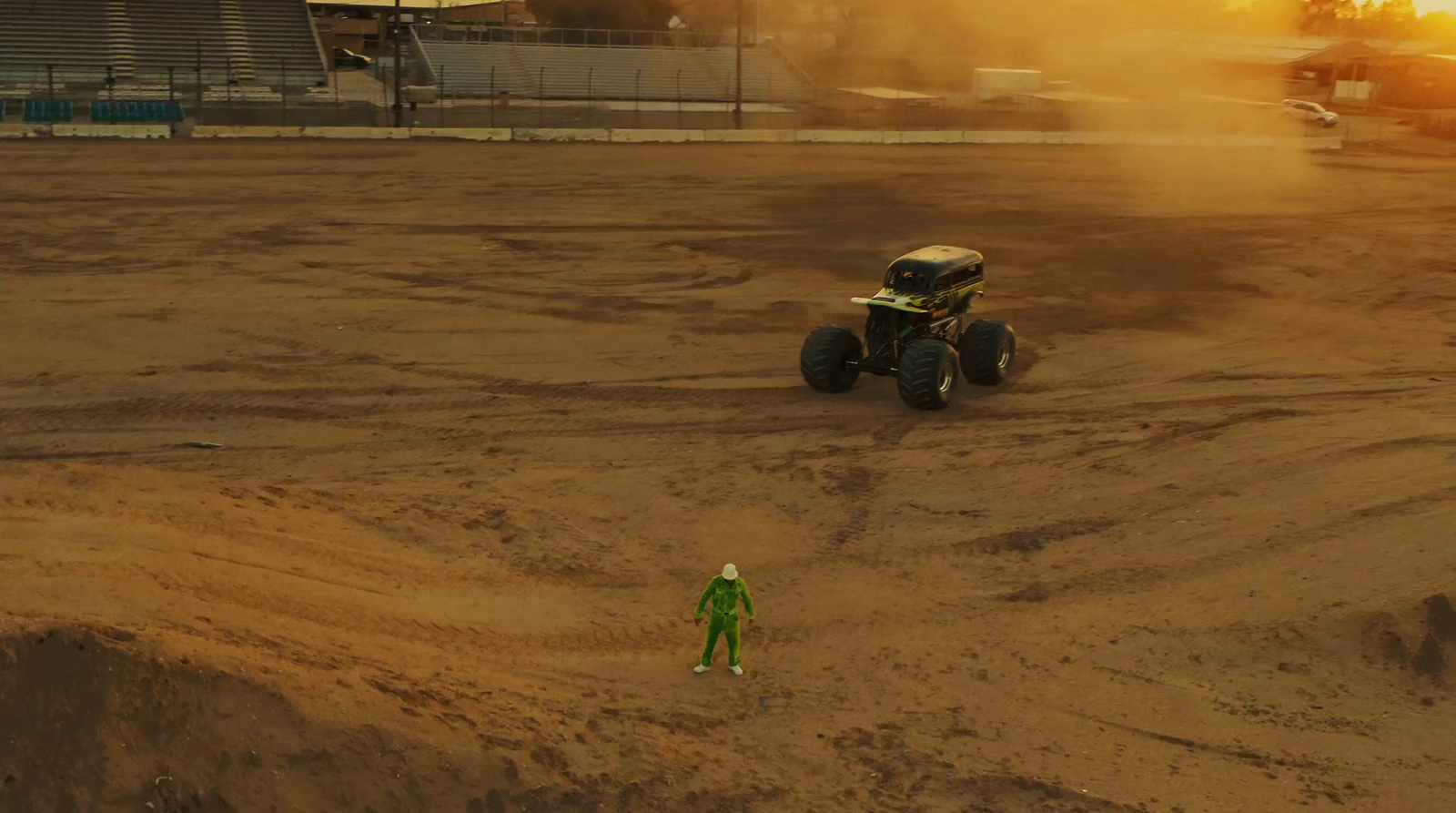 a person standing in a dirt field next to a monster truck